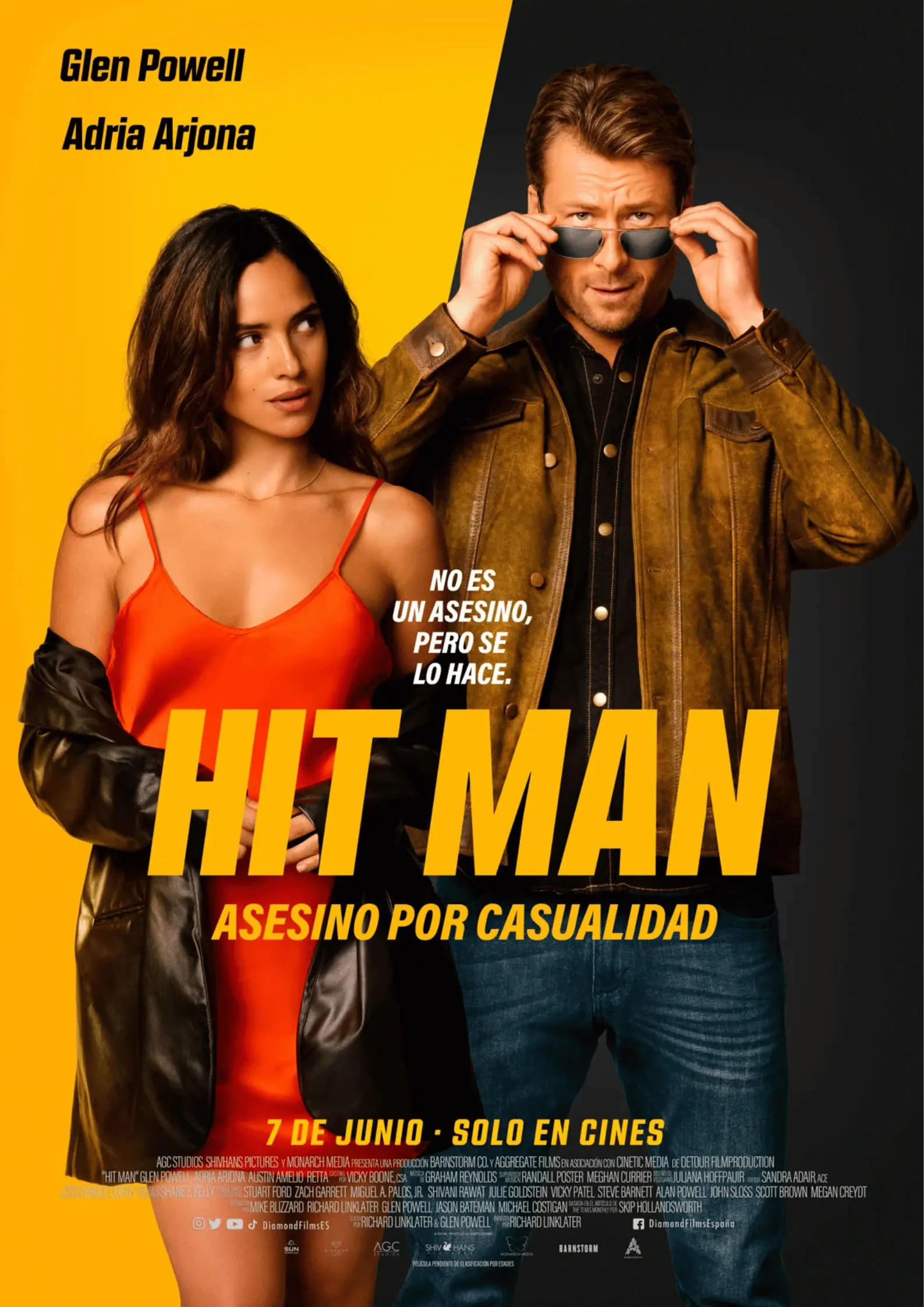 Hit Man movie poster starring Glen Powell and Adria Arjona in front of bright yellow studio backdrop